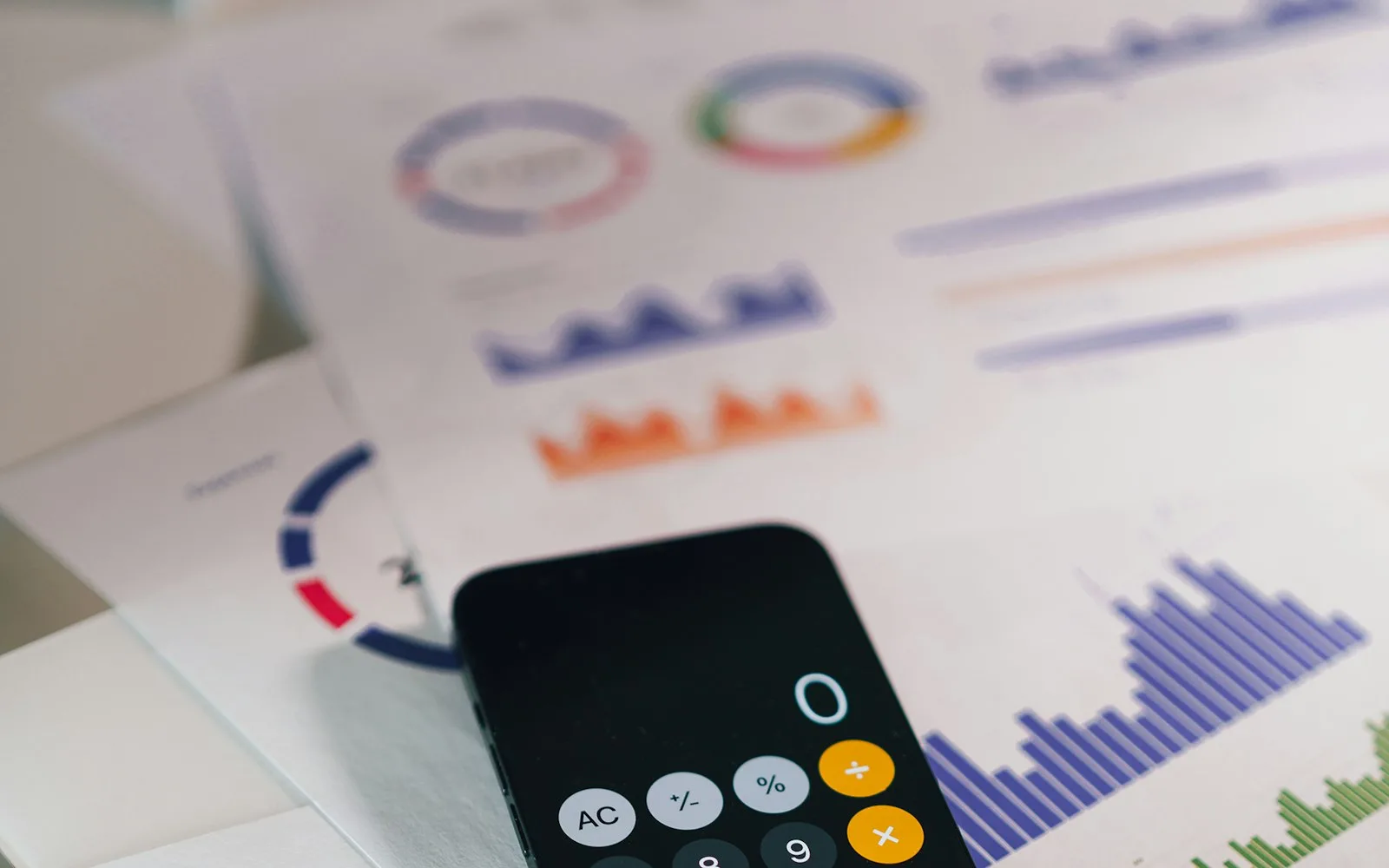 Mali rapor kâğıtlarının üzerinde hesap makinesi uygulaması açık bir telefon