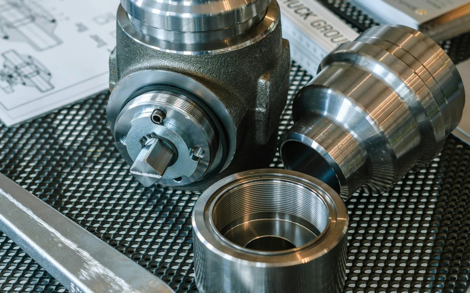 Teknik çizimlerin üzerinde duran metal makine parçaları