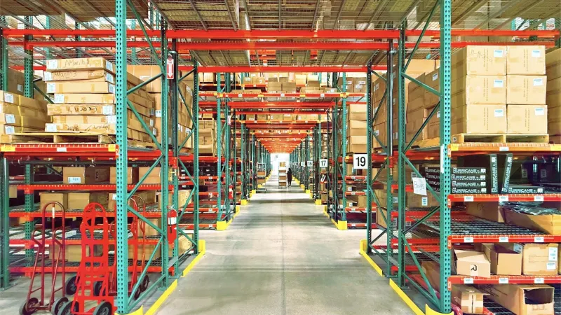 A wide warehouse aisle lined with tall shelves full of boxes